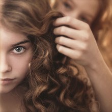 Caucasian girl braiding friend's hair