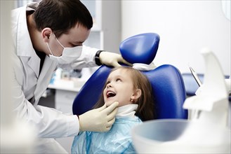 Caucasian dentist examining girl's teeth