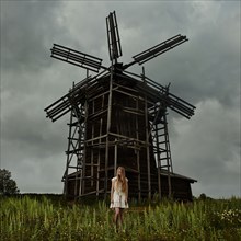Caucasian teenage girl standing under wooden windmill