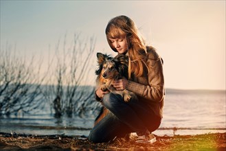 Caucasian girl petting dog near remote lake