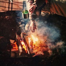 Caucasian girl warming hands above campfire