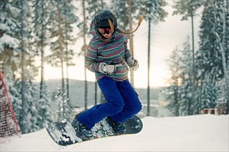 Caucasian girl riding snowboard in snow
