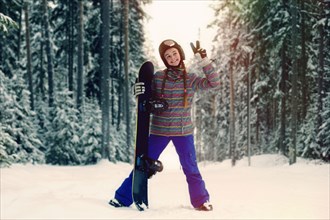 Caucasian snowboarder making peace sign in snowy forest