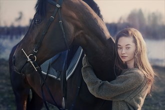 Caucasian woman hugging horse in field