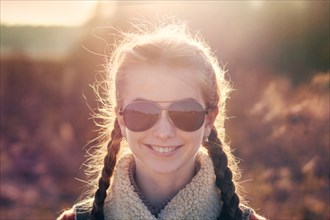 Caucasian teenage girl wearing sunglasses in field