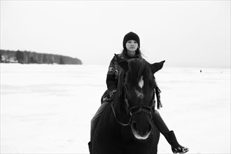 Caucasian teenage girl riding horse in snowy field