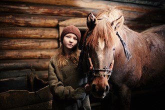Caucasian teenage girl standing with horse in barn