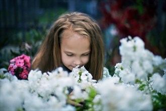 Caucasian girl smelling flowers in garden