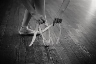 Caucasian ballerina tying pointe shoes