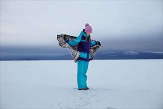 Caucasian teenage girl wrapped in blanket in snow