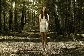 Barefoot Caucasian woman standing in forest