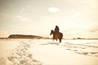 Caucasian man riding horse in snowy landscape