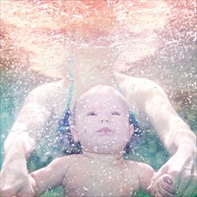 Caucasian mother and preschooler son swimming underwater