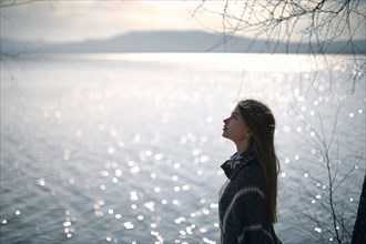 Pensive Caucasian girl at lake looking up