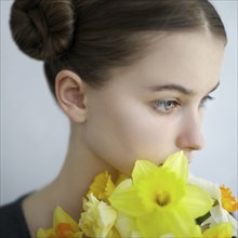 Pensive Caucasian girl holding yellow flowers