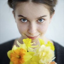 Smiling Caucasian girl holding yellow flowers