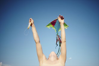 Caucasian girl with arms raised flying kite