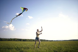 Caucasian girl running in field flying kite