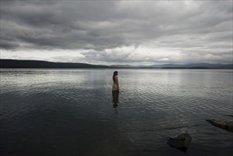 Caucasian girl wading in lake