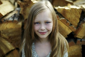 Caucasian girl smiling near woodpile