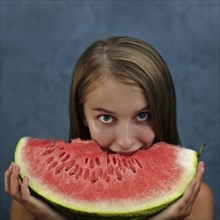 Caucasian girl eating enormous slice of watermelon