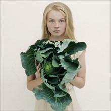 Caucasian girl holding leafy green lettuce