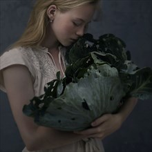 Caucasian girl smelling leafy green lettuce