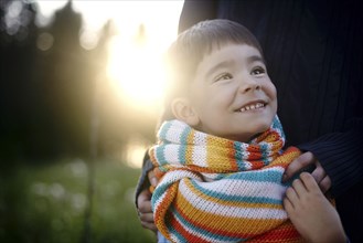 Caucasian woman holding shoulders of boy wearing multicolor scarf