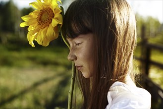 Profile of Caucasian girl with freckles holding sunflower