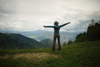 Caucasian girl stretching arms on mountain range