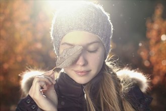 Caucasian teenage girl covering eye with leaf