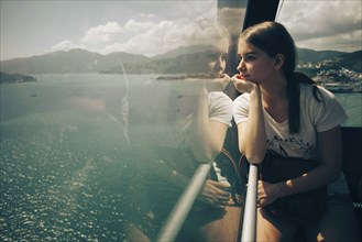 Caucasian woman looking out window on boat