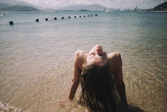 Caucasian woman wearing bikini sitting in waves on beach