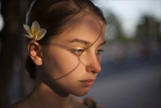 Pensive Caucasian woman with flower in hair