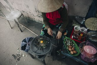 Woman cooking egg on grille