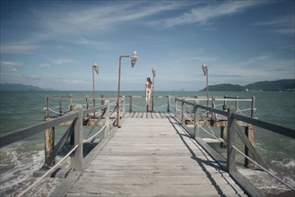 Caucasian woman wearing bikini standing on railing on dock