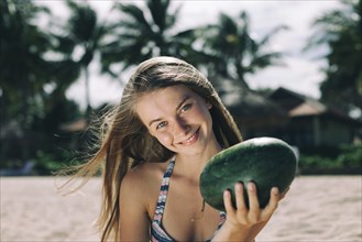 Caucasian woman holding watermelon on beach