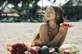 Caucasian woman eating watermelon on beach