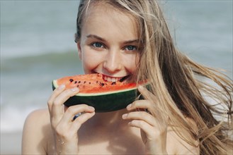 Caucasian woman eating watermelon on beach