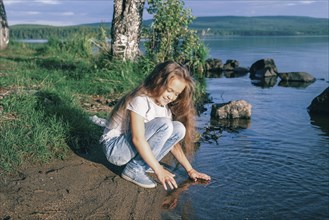 Caucasian girl crouching near river