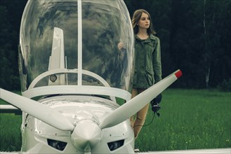 Caucasian woman standing near an airplane cockpit