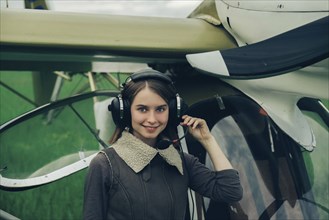 Caucasian woman wearing a headset near airplane