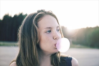 Caucasian teenage girls blowing bubbles with gum