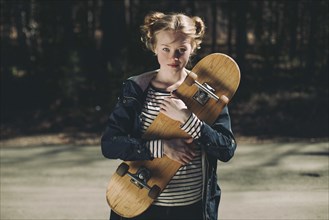 Portrait of Caucasian teenage girl holding skateboard