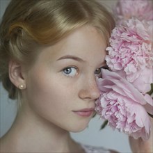 Close up of Caucasian teenage girl holding flowers to face
