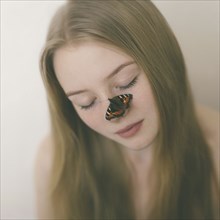 Butterfly on nose of Caucasian teenage girl