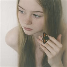 Butterfly on fingers of Caucasian teenage girl