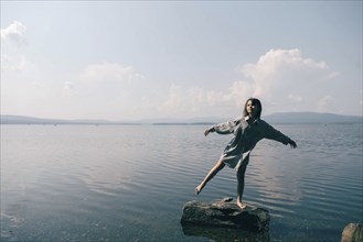 Caucasian girl standing on rock in lake