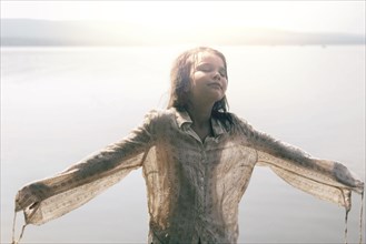 Caucasian girl wearing wet shirt near sunny lake