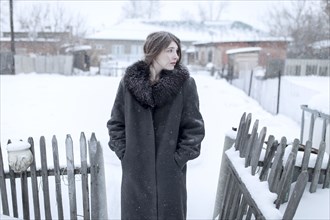 Caucasian woman wearing coat in winter near fence